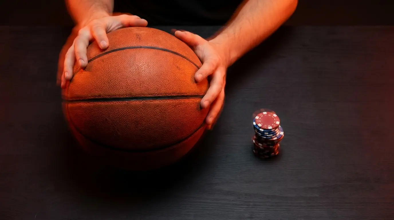 Handen met basketbal en stapel gokfiches op tafel
